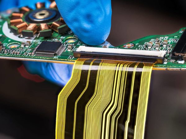 Hand in blue glove holding green PCB with integrated motor stator and electronic components as micro chip or resistors. Surface mount technology